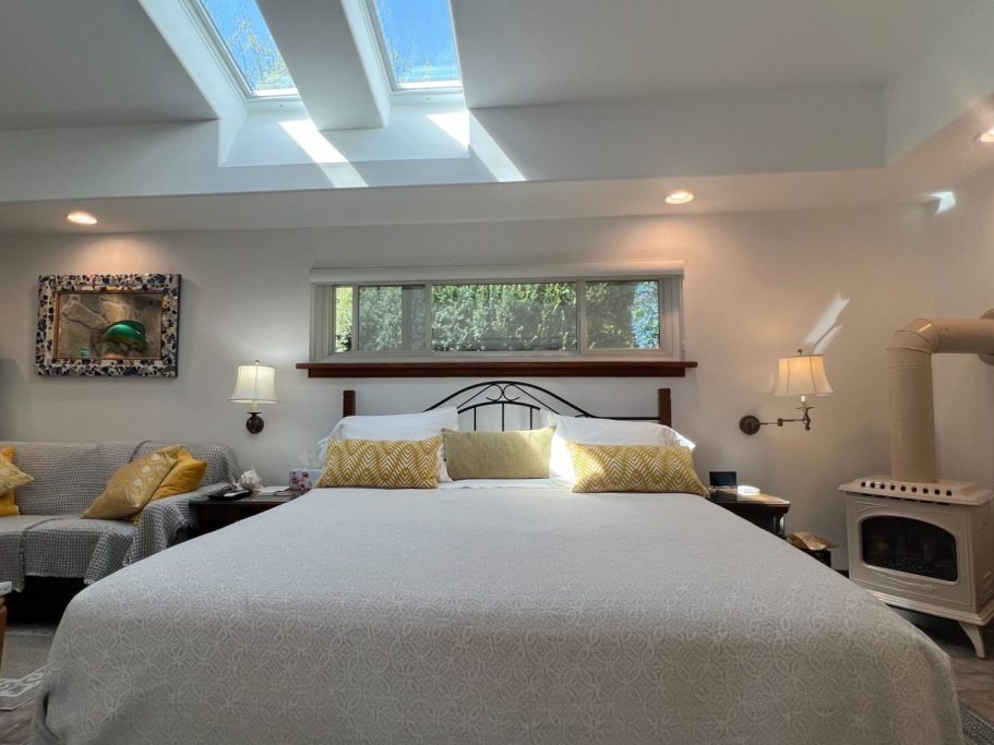 King Bed and Cathedral Skylights Stearns & Foster king bed centred under bright cathedral skylights with a bedside gas wood-stove in the luxury suite.