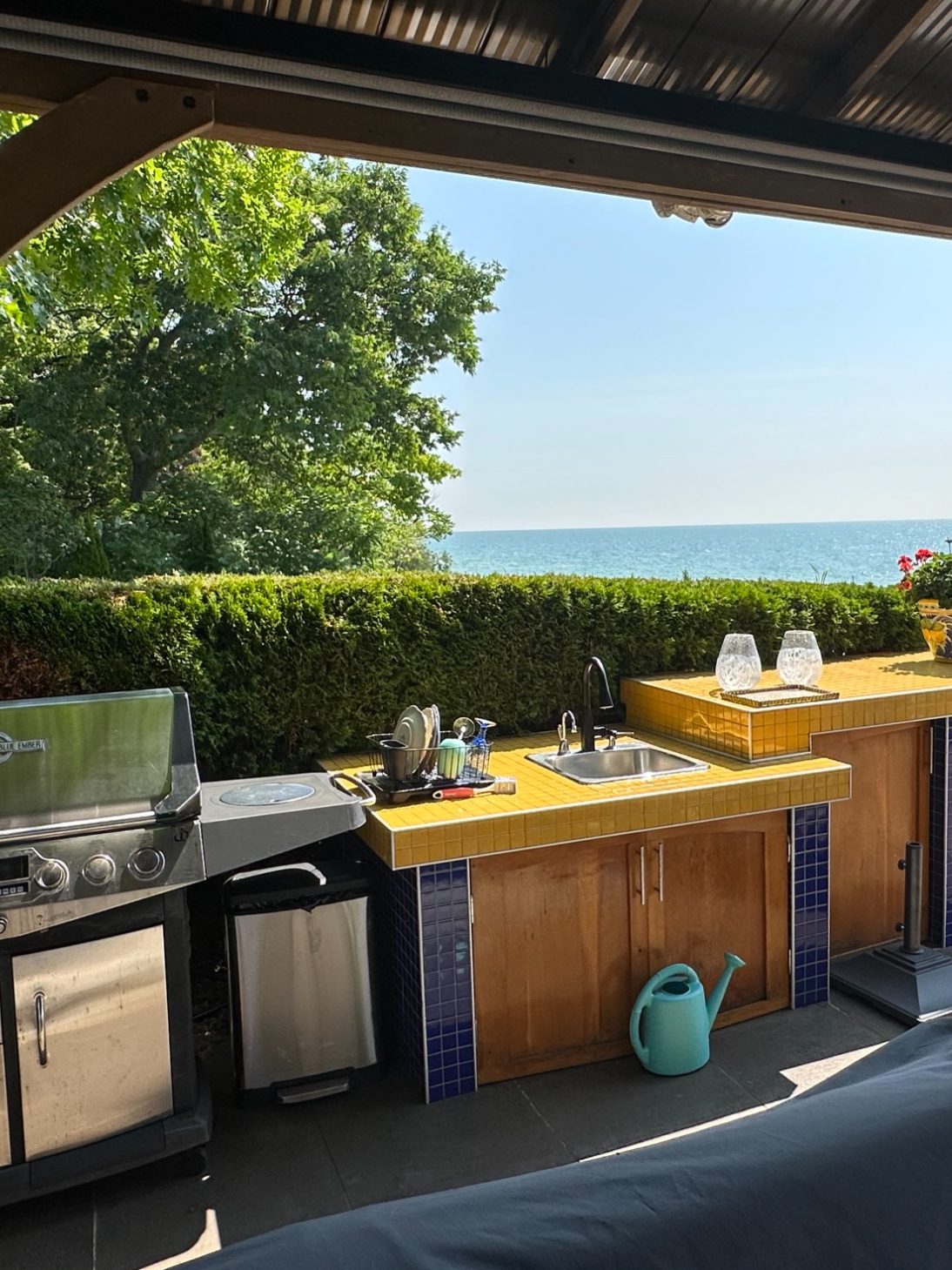 Luxury Outdoor Kitchen and BBQ Area Outdoor kitchen with BBQ grill, yellow tiled countertop, and sink overlooking Lake Ontario at Wind in the Willows Oasis.