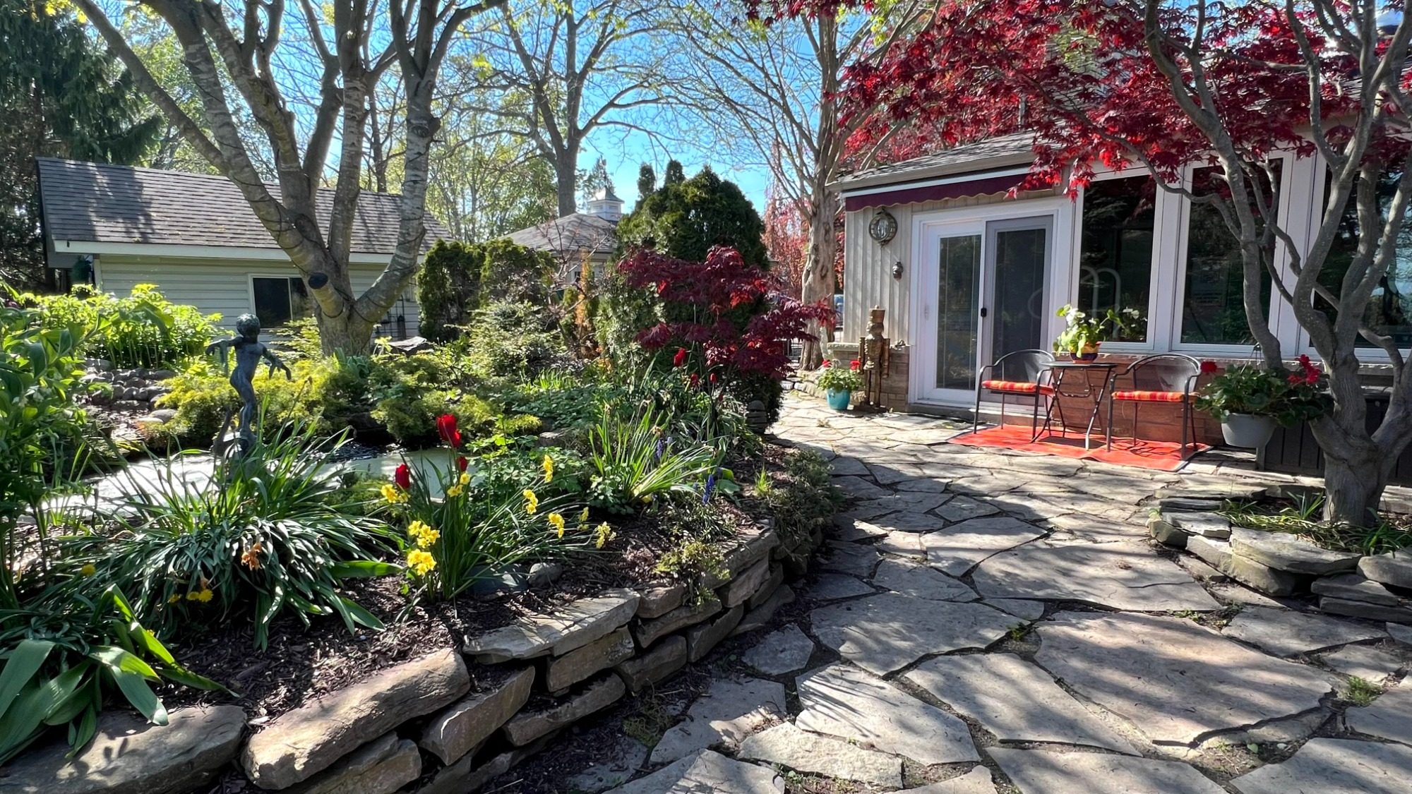 Private Guest Suite Entrance and Gardens Flagstone patio walkway leading to the private guest suite entrance surrounded by lush spring gardens and mature trees at Wind in the Willow