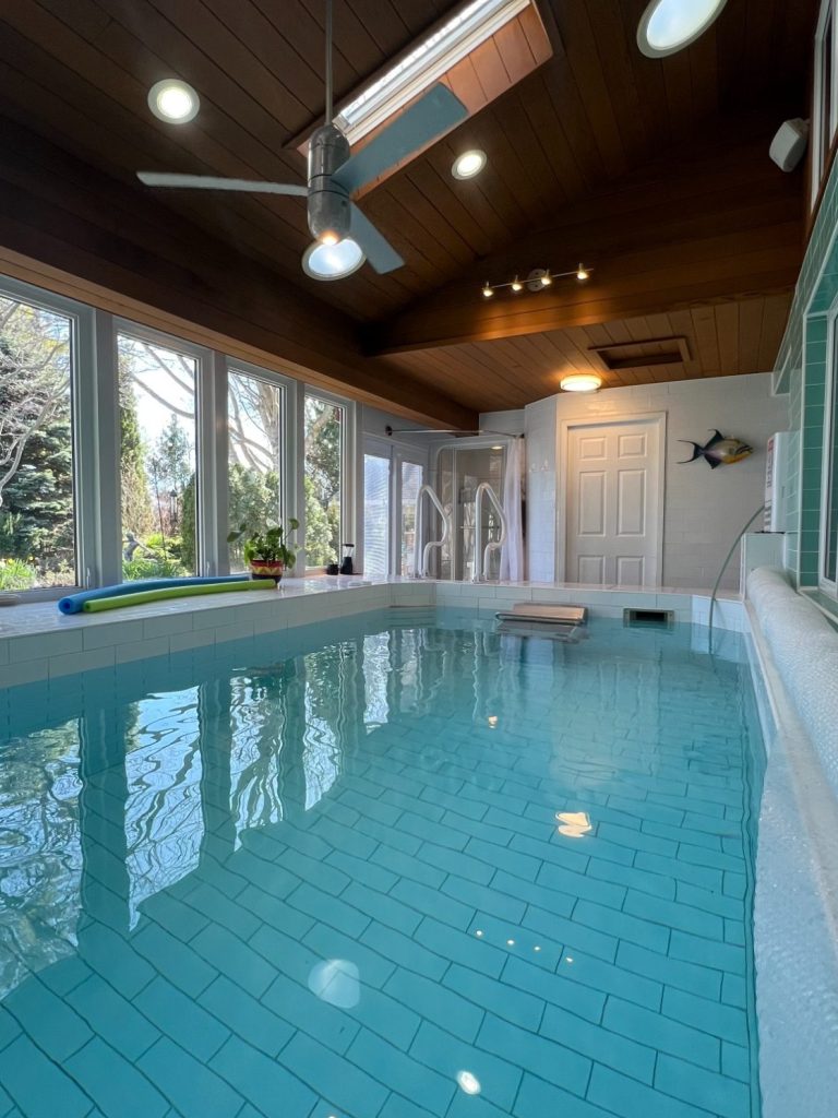 Private Indoor Pool with Stained Cedar Ceiling Heated luxury indoor pool with an endless swim machine, stained cedar ceilings, and large windows looking out to the gardens at Wind in the